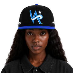 A model wearing a black snapback cap with a blue brim and a blue and white embroidered 'VR' logo on the front, set against a plain light gray background.